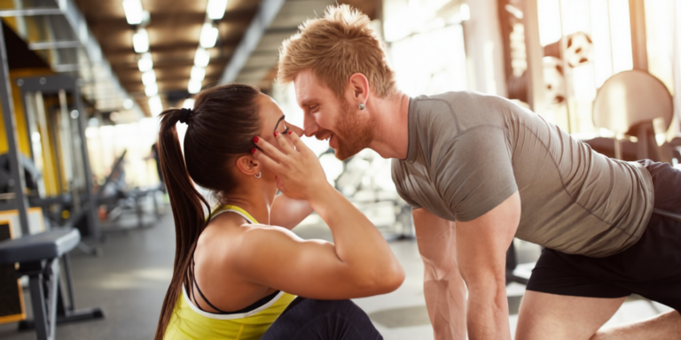 een man en vrouw in een sportschool die elkaar aanraken en glimlachen