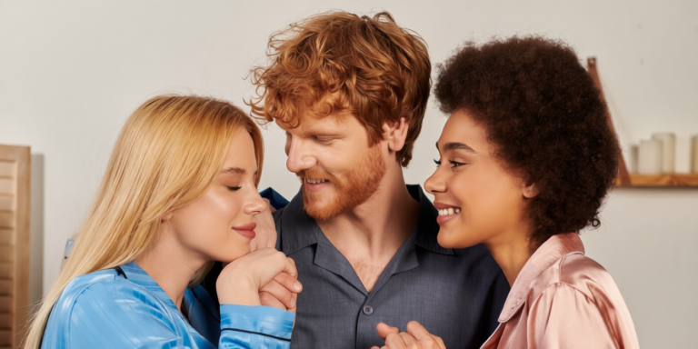 een vrouw met blond haar en een vrouw met krullend haar kijken naar een man met rood haar en glimlachen