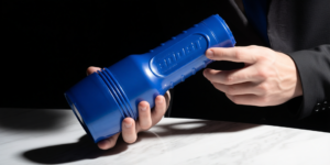 een mannelijke hand houdt een blauwe fleshlight masturbator vast
