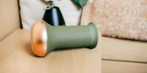 een groen en koperkleurige masturbator op een houten tafel