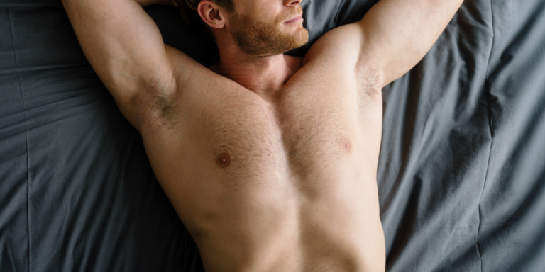naakte borst van een man met baard die op een bed ligt