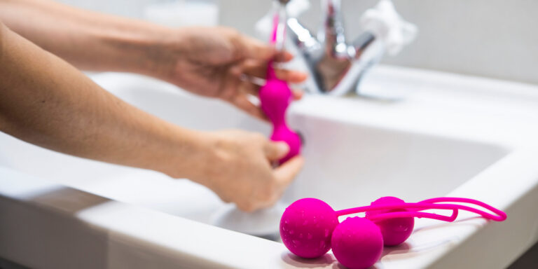 handen die een roze geisha ballen onder de kraan wassen, met twee andere op het aanrecht