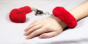 een hand met rode pluche boeien op een witte ondergrond