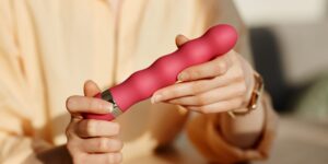 een vrouw houdt een roze vibrator vast