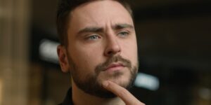 man met baard en blauwe ogen die peinzend naar boven kijkt