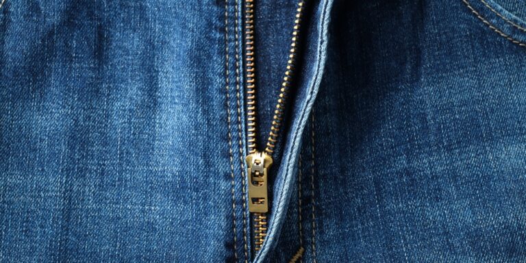 close-up van een metalen rits op een blauwe denim broek