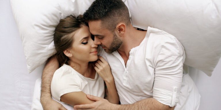 een man en vrouw liggen in bed en kijken elkaar liefdevol aan